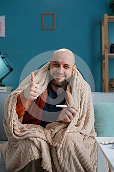Happy man with a thermometer in his hands recovery, victory over the disease