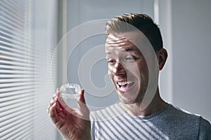 Happy man with toothy smile holding whitening trays