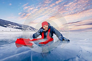 Happy man tourist in red cap bites transparent ice in winter on Lake Baikal