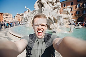 Happy man tourist taking selfie photo on background fountain Four rivers in Piazza Navona, Rome Italy