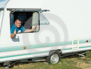 Happy man in a tourist trailer. caravan trailer of large size, ensure the comfort of the traveler. recreational vehicle RV. summer