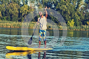 Happy man is training on a SUP board