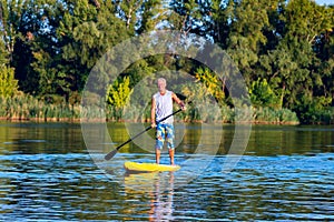 Happy man is training on a SUP board