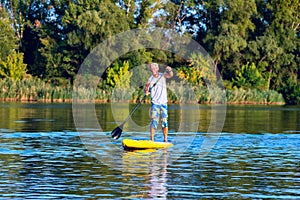 Happy man is training on a SUP board