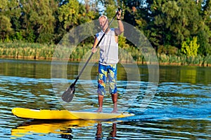 Happy man is training on a SUP board