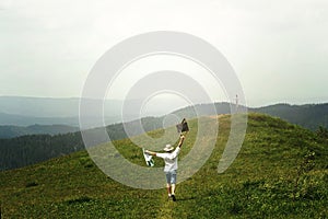 Happy man traveler holding map and running to top of sunny hill