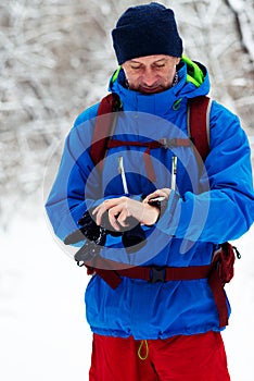Happy man, traveler looks at his watch while walking in the winter forest