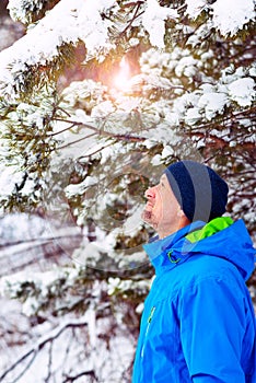 Happy man, traveler walking in the winter forest during snowfall