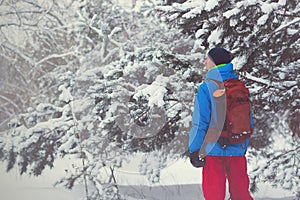 Happy man, traveler walking in the winter forest during snowfall