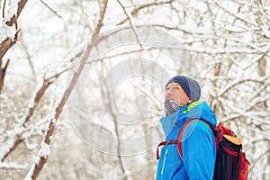 Happy man, traveler walking in the winter forest during snowfall