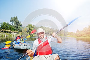 Happy man with two kids enjoying kayak ride on beautiful river. Father with little boy and teenager girl kayaking on hot