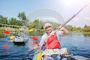 Happy man with two kids enjoying kayak ride on beautiful river. Father with little boy and teenager girl kayaking on hot