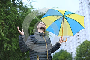 Happy man with umbrella outdoors on rainy day