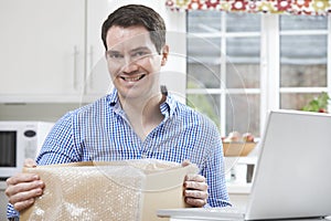 Happy Man Unpacking Online Purchase At Home