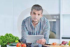 Happy man using digital tablet in kitchen at home