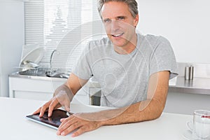 Happy man using digital tablet in kitchen