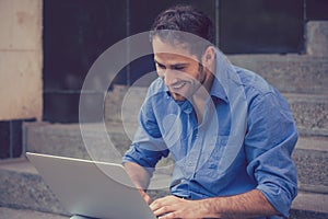 Happy man using his laptop computer outdoors smiling