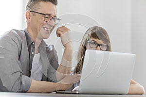 Happy man using laptop with daughter at home