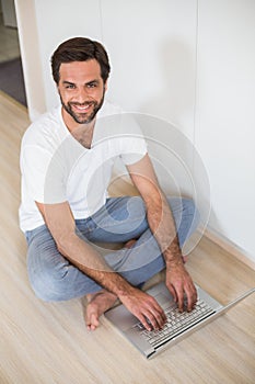 Happy man using laptop on floor