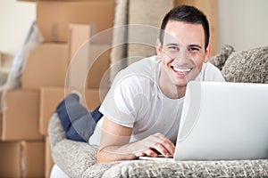 Happy man using laptop in his new home