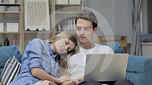 Happy Man Using Laptop while Sleeping Girlfriend Head on His Shoulder