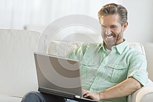 Happy Man Using Laptop On Sofa