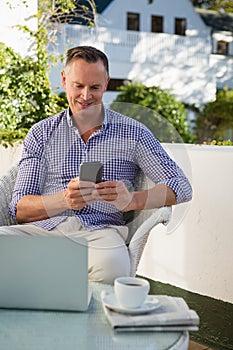 Happy man using mobile phone while sitting in cafe