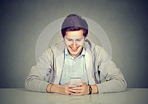 Happy man using mobile phone sitting at table