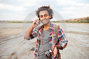 Happy man with vintage photo camera talking on mobile phone
