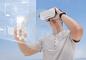 Happy man in VR headset touching interface against blue background