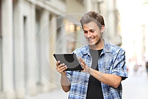 Happy man walking browsing tablet online content