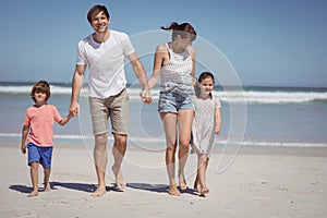 Happy man walking with his family while holding hands at beach