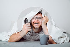 Happy man watch TV under blanket