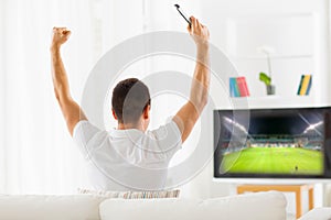 Happy man watching football on tv at home