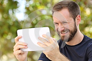 Happy man watching videos in a ereader tablet