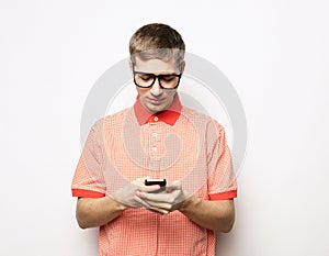 Happy man wearing casual shirt in glasses typing sms on gray background