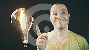 Happy man wearing green t-shirt and glowing light bulb. Inspiration or ecological energy concepts