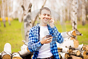 Happy man wearing headphones listening to music checking smart phone walking in park