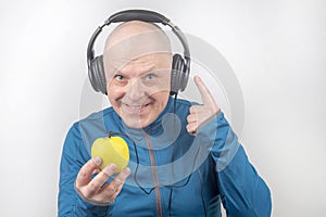 Happy man wearing portable full-size headphones listens to music using an apple player