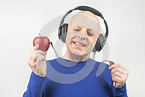 Happy man wearing portable full-size headphones listens to music using an apple player