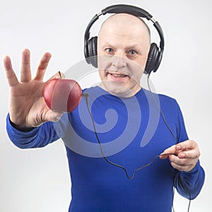 Happy man wearing portable full-size headphones listens to music using an apple player