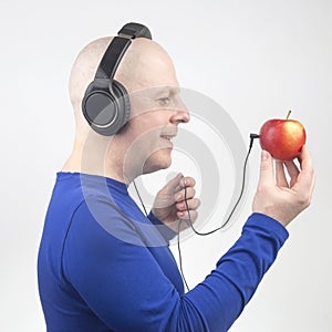 Happy man wearing portable full-size headphones listens to music using an apple player