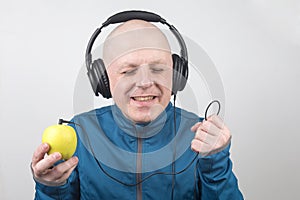 Happy man wearing portable full-size headphones listens to music using an apple player