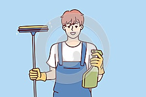 Happy man window cleaner holds spray bottle with detergent and mop for cleaning glass