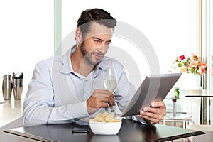 Happy man with wine and tablet at the bar