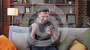 Happy man winner feeling excited celebrating victory online on mobile phone.