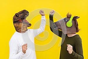 Happy man and woman with dinosaur and horse head mask dancing. Active couple ,positive and celebration people lifestyle, isolated