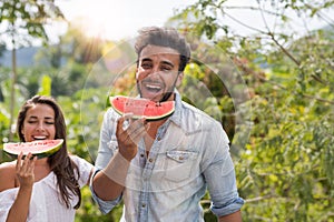 Happy Man And Woman Eating Watermelon Together Over Beautiful Tropical Forest Landscape Cheerful Couple Laugh Holding