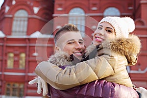 Happy man and woman embrace near red building at