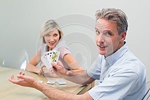 Happy man and woman playing cards at home